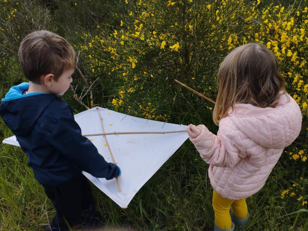 deux enfants tiennent une toile blanche et un baton : un parapluie japonais pour observer les insectes des buissons