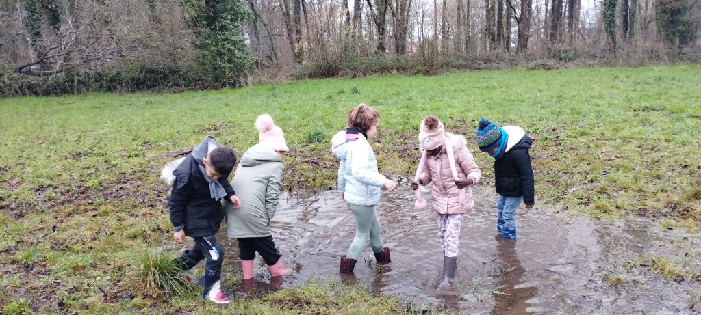 des enfants en bottes pataugent dans une flaque d'eau